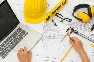 Sarı kask ve çizim aracı ile inşaat planları teslim