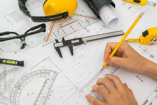 Entregar planos de construção com capacete amarelo e ferramenta de desenho — Fotografia de Stock