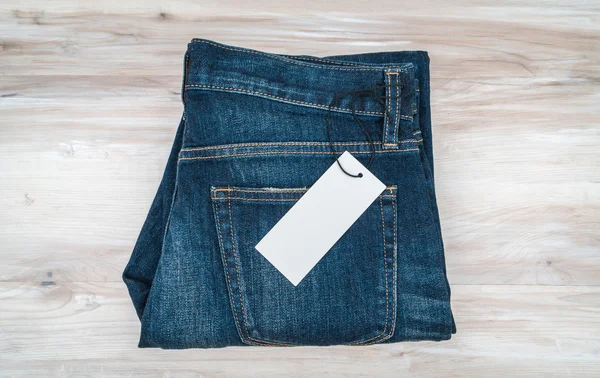 Calça jeans azul com preço no fundo de madeira  . — Fotografia de Stock