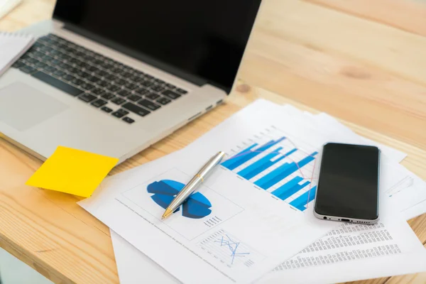 Financial charts on the table with laptop and phone . — Stock Photo, Image