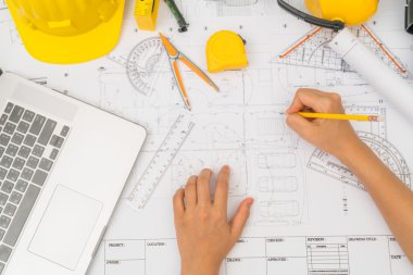 Sarı kask ve çizim aracı ile inşaat planları teslim