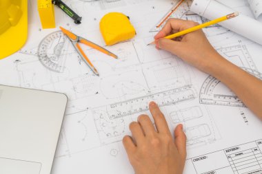 Sarı kask ve çizim aracı ile inşaat planları teslim