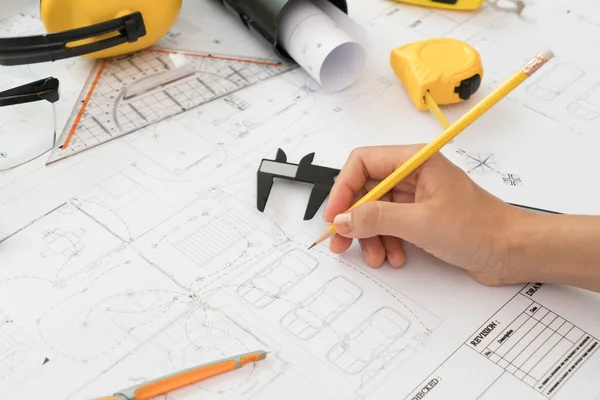 Lämna över byggnadsplanerna med gul hjälm och ritverktyg — Stockfoto