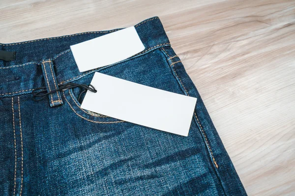 Calça jeans azul com preço no fundo de madeira  . — Fotografia de Stock