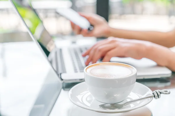 Close-up van de koffie van de Latte art en vrouw hand typen op laptop sleutel — Stockfoto