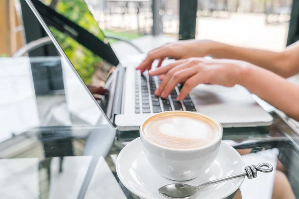 Close-up van de koffie van de Latte art en vrouw hand typen op laptop sleutel — Stockfoto