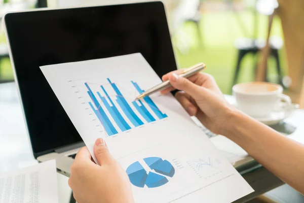 Mão de mulher de negócios com gráficos financeiros e laptop na mesa — Fotografia de Stock