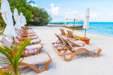 Plaj sandalyeleri beyaz kumlu b ile Maldivler Adası'nda şemsiye ile