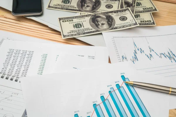 Financial charts on the table with laptop , phone ,dollars bankn — Stock Photo, Image