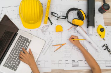 Sarı kask ve çizim aracı ile inşaat planları teslim