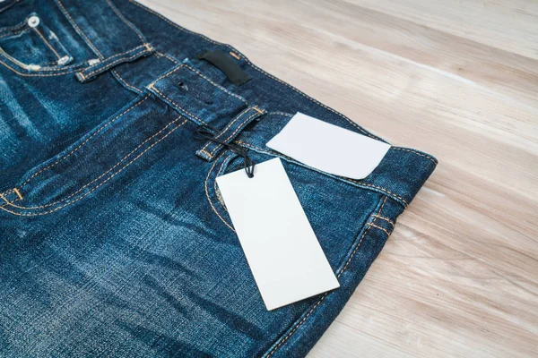 Niebieskie jeansy z ceną na podłoże drewniane . — Zdjęcie stockowe