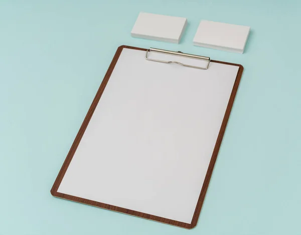 Clip board, paper and business card on blue background .