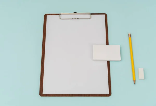 Clip board, paper,pencil  and business card on blue background .
