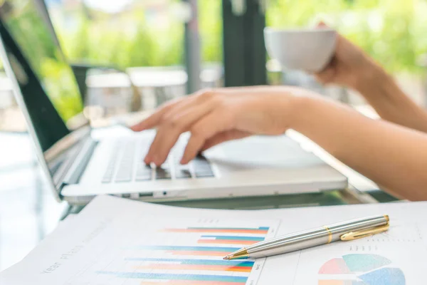 Mão de mulher de negócios com gráficos financeiros e laptop na mesa — Fotografia de Stock