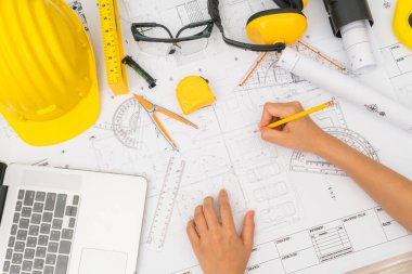 Sarı kask ve çizim aracı ile inşaat planları teslim