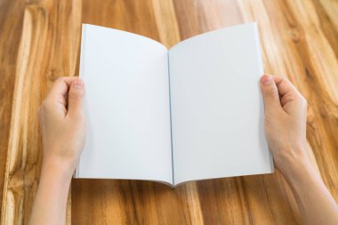 Ahşap masa üzerinde eller açık kitap .