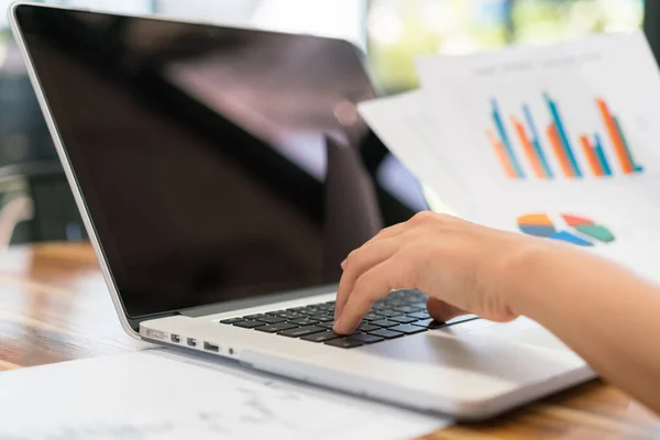 Mão de mulher de negócios com gráficos financeiros e laptop na mesa — Fotografia de Stock