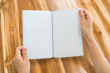 Ahşap masa üzerinde eller açık kitap .