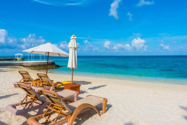 Plaj sandalyeleri beyaz kumlu b ile Maldivler Adası'nda şemsiye ile