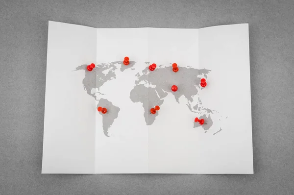 Mapa del mundo plegado de papel con puntero de pasador rojo . — Foto de Stock