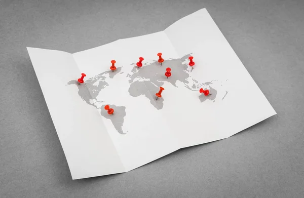 Carta piegato mappa del mondo con puntatore di perno rosso . — Foto Stock