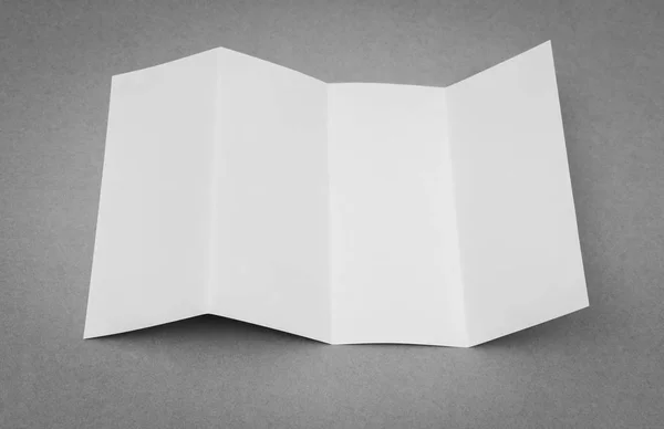 Τέσσερις - Διπλώστε το πρότυπο λευκό χαρτί σε γκρίζο φόντο . — Φωτογραφία Αρχείου