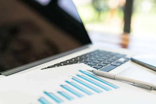 Gráficos financieros sobre la mesa con portátil  . — Foto de Stock