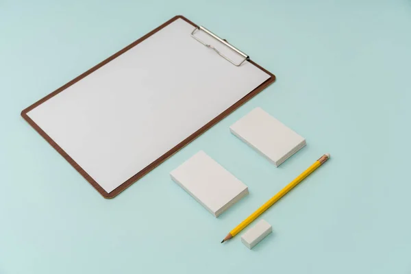 Clipboard, Papier, Bleistift und Visitenkarte auf blauem Hintergrund . — Stockfoto