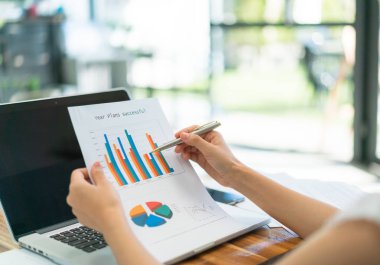 Kapalı toplantıda laptop ve mali grafikleri kullanarak iş adamları