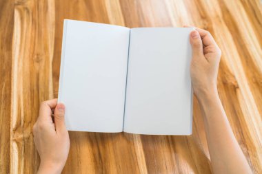 Ahşap masa üzerinde eller açık kitap .