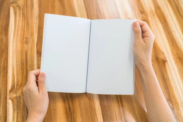 Manos libro abierto sobre mesa de madera  . — Foto de Stock