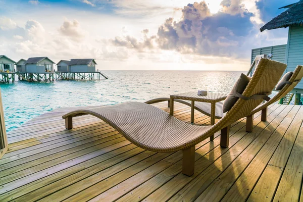 Two deck chairs on the wooden floor in water villa sunset time , — Stock Photo, Image