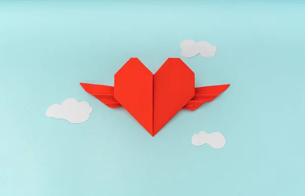 Papel vermelho origami coração com asas e nuvem no fundo azul — Fotografia de Stock
