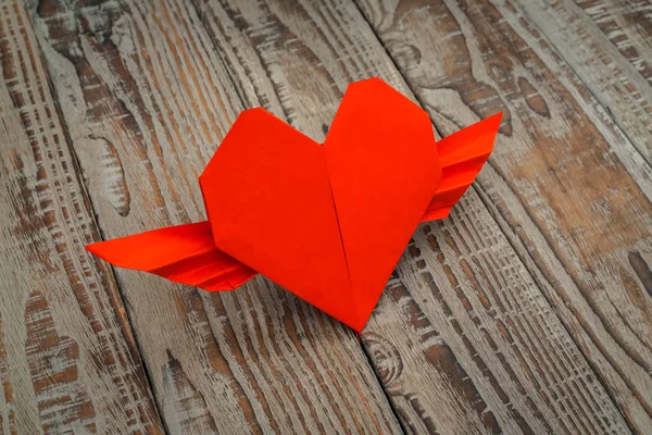 Red paper origami heart with wings on wood background . — Stock Photo, Image