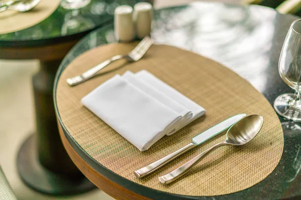 Mesa de citas tenedor, cuchillo, cuchara, servilleta de seda en estera de bambú — Foto de Stock