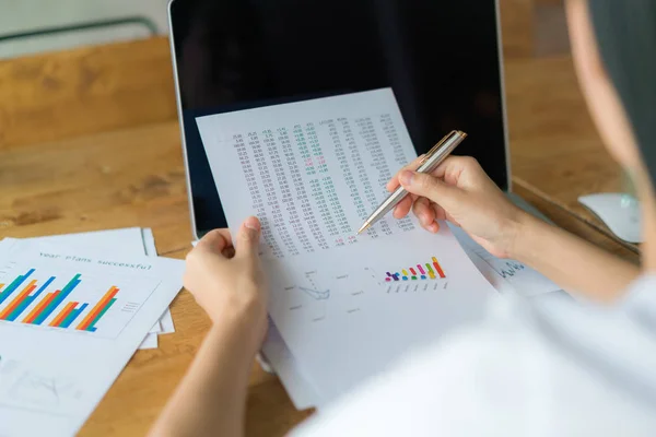 Femme d'affaires main avec des tableaux financiers et ordinateur portable sur la table — Photo