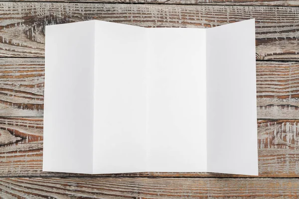 Cuatro: pliegue el papel de plantilla blanco sobre la textura de madera  . — Foto de Stock