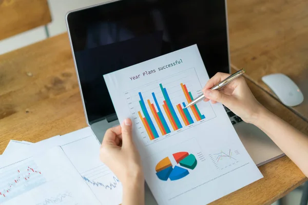 Femme d'affaires main avec des tableaux financiers et ordinateur portable sur la table — Photo