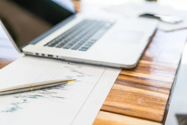 Gráficos financieros sobre la mesa con portátil  . — Foto de Stock