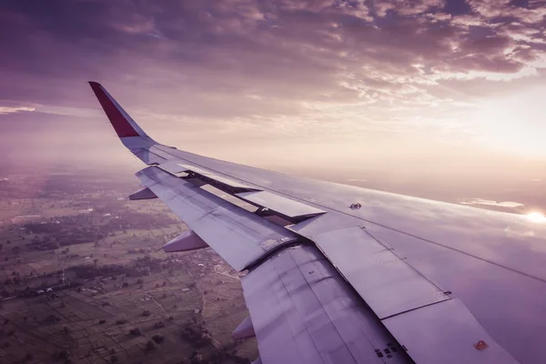 Ala de un avión volando por encima de las nubes al atardecer. (Filtro —  Fotos de Stock