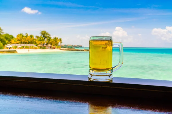 A glass of beer with Beautiful tropical Maldives island .