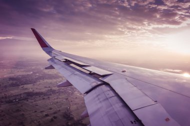 Gün batımında bulutların üzerinde uçan bir uçağın kanat. (Filtre