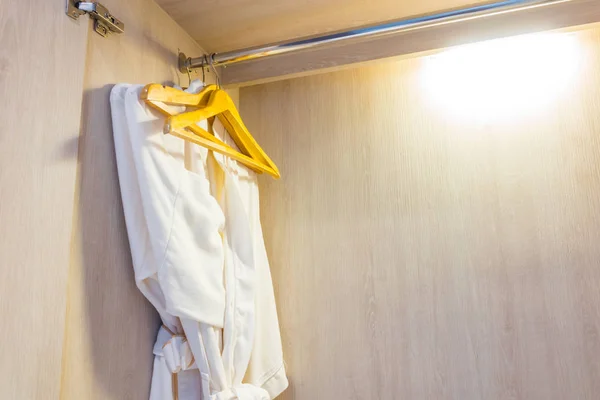 White bathrobe in wooden wardrobe of luxury hotel . — Stock Photo, Image