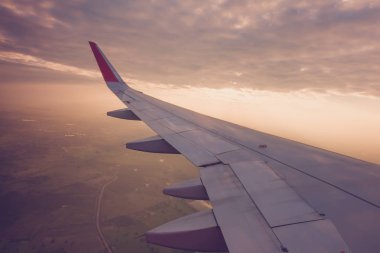 Gün batımında bulutların üzerinde uçan bir uçağın kanadı (filtrelenmiş görüntü işlenmiş vintage etkisi. )