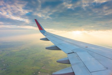 gün batımında bulutların üzerinde uçan bir uçağın kanat