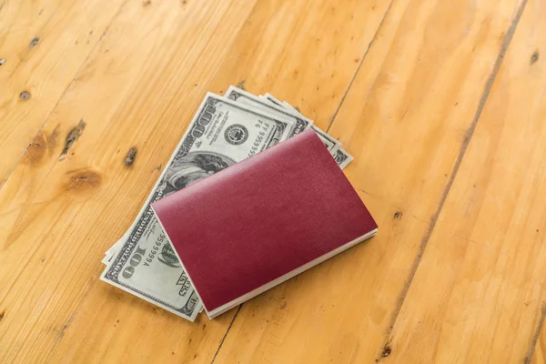 Passaporte em branco com dólares americanos na mesa de madeira   . — Fotografia de Stock