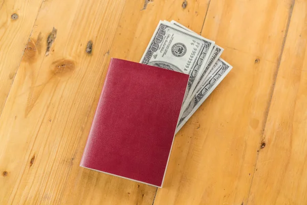 Passaporte em branco com dólares americanos na mesa de madeira   . — Fotografia de Stock
