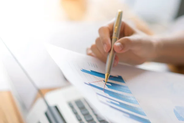 Business kvinna hand med finansiella diagram och laptop på bordet — Stockfoto