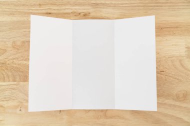 A4 üç katlı boş beyaz şablon modeli ve ahşap yüzey üzerine sunum tasarımı. 