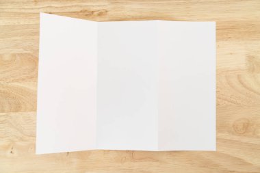 A4 üç katlı boş beyaz şablon modeli ve ahşap yüzey üzerine sunum tasarımı. 